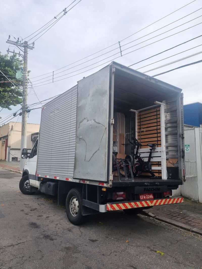 Caminhão com o baú aberto e a mudança organizada e amarrada